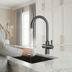 Person washing a white mug under a black kitchen faucet in a modern kitchen.